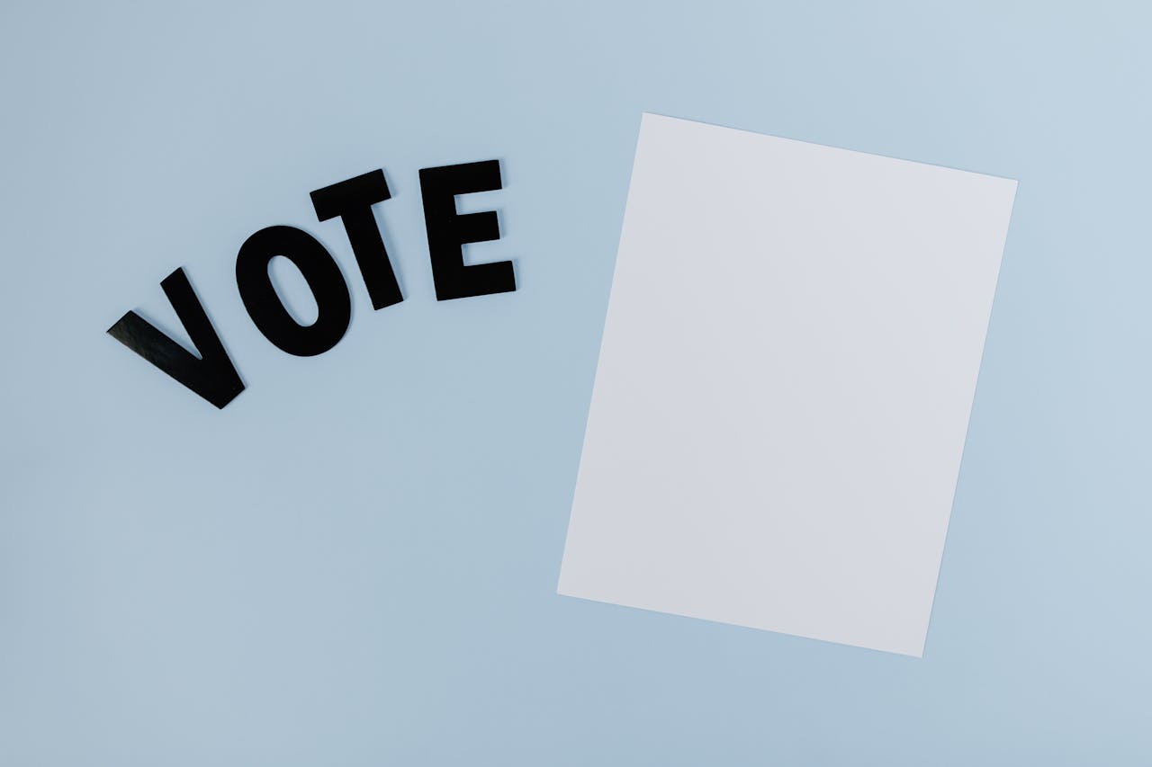 services-01 Flat lay of blank paper with 'VOTE' letters on light blue background, ideal for election-themed content.